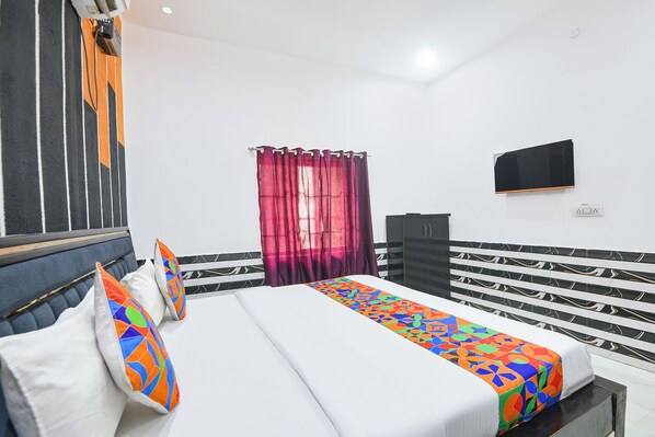 A hotel room with a bed, a TV, a wardrobe, and a window with curtains. - Fabhotel Vrindavan Dham (Vrindavan)