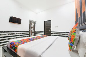 Et hotelværelse med en seng, et fjernsyn, en dør og tapet.