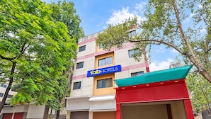 Un edificio de varios pisos con un letrero 'fabHOTELS', un toldo rojo y una puerta de garaje cerrada.