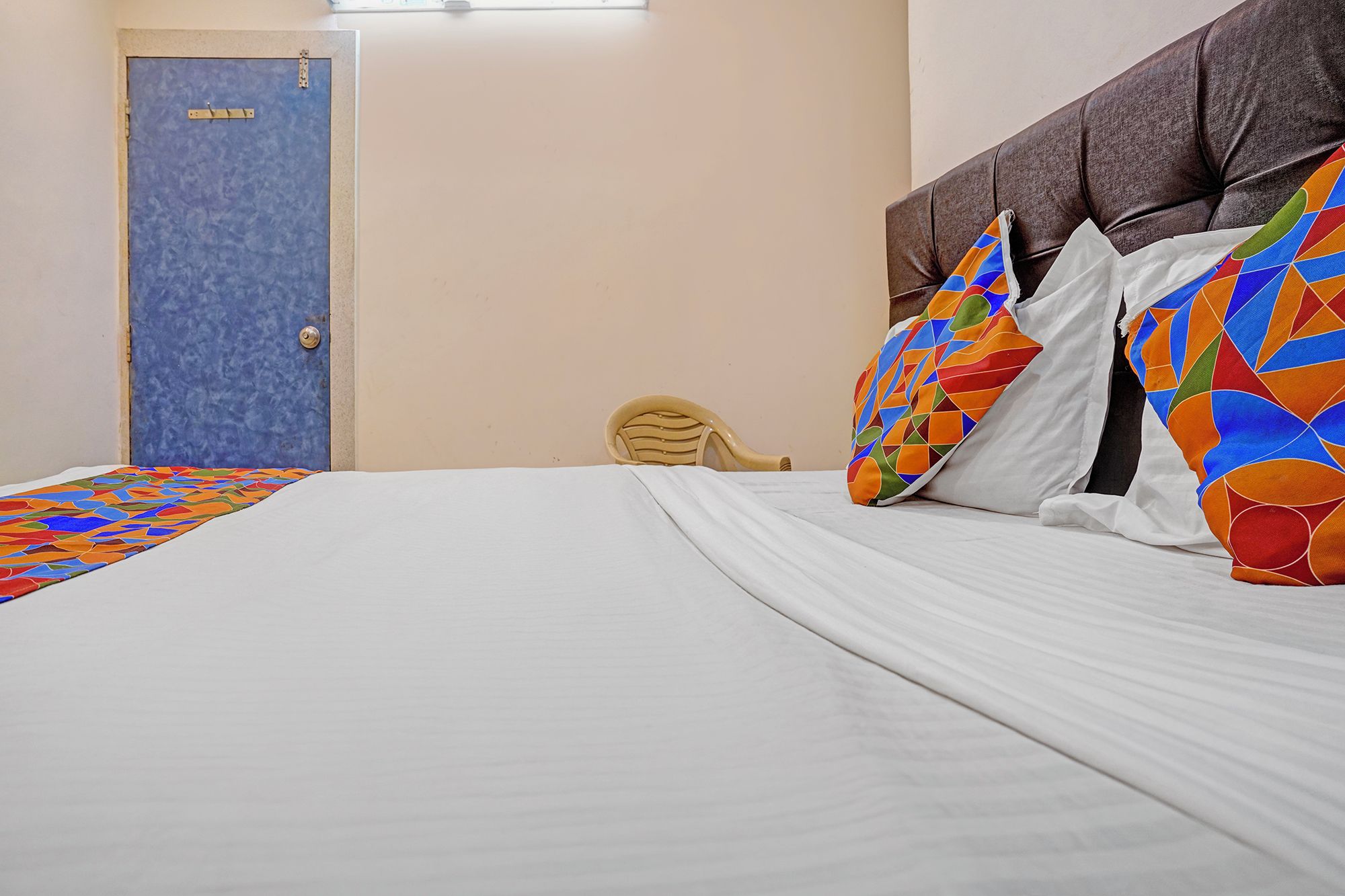 Une chambre d’hôtel avec un lit, une porte et une chaise.