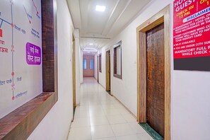 A hotel corridor with a check-in desk, wooden doors, and a signboard with text. - FabHotel Sai Seva (Nashik)