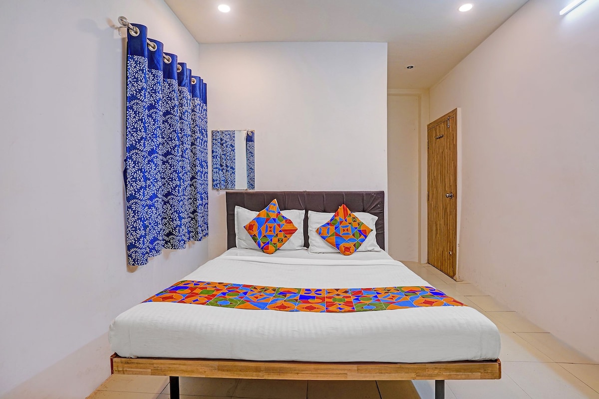 A narrow hallway leading to a bed with a white headboard and colorful geometric-patterned pillows.