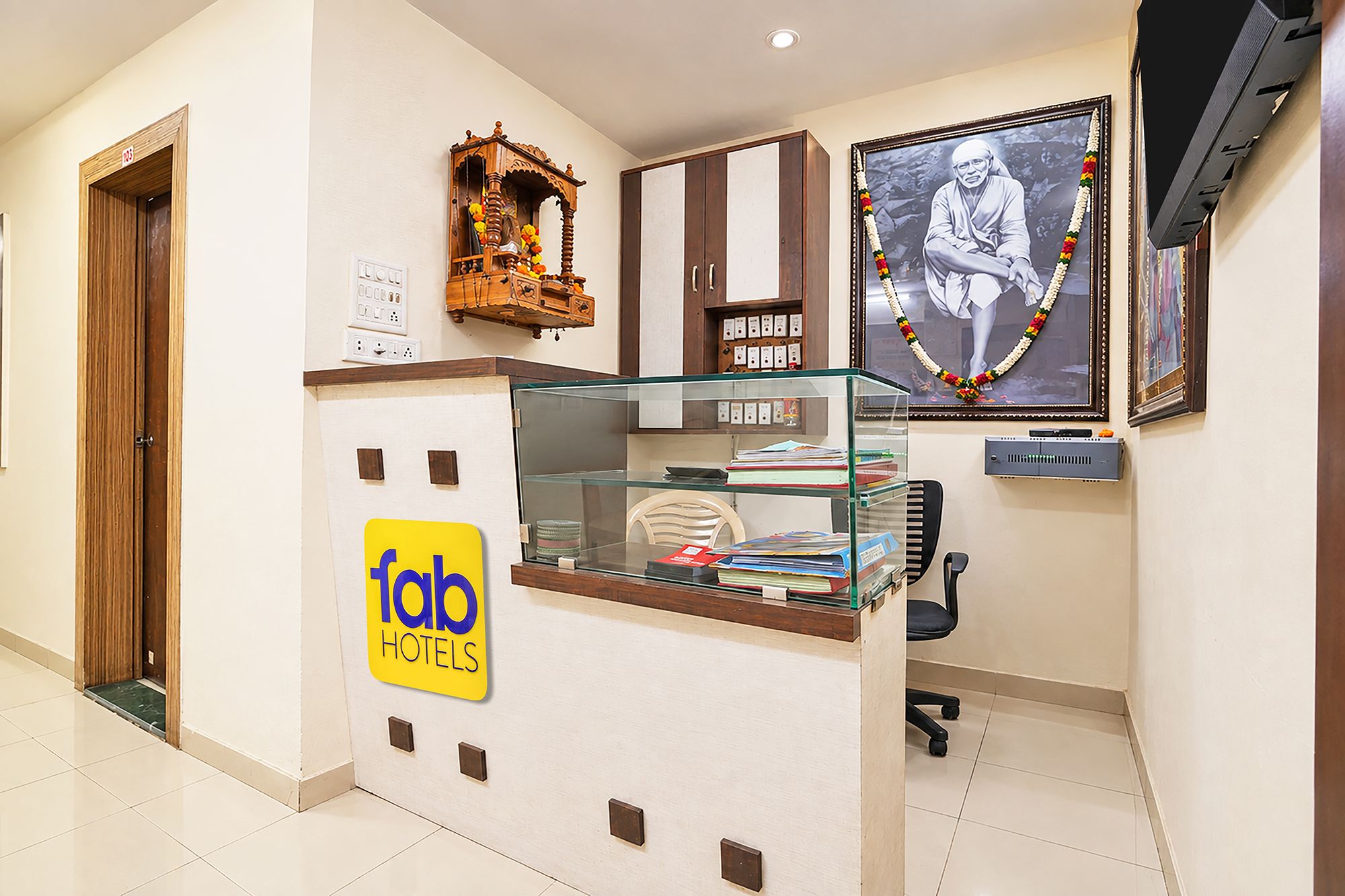 Zona de recepción de un hotel con un expositor de vidrio, un mueble de madera y una fotografía enmarcada en la pared.