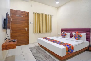 Una habitación de hotel con una cama, un armario de madera, un televisor y una ventana con cortinas.