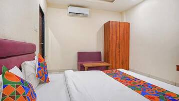 A bedroom with a bed, a wardrobe, a chair, and an air conditioning unit.
