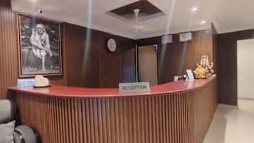 Zona de recepción con un mostrador de madera, un reloj y un cuadro en la pared.