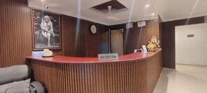 A reception area with a wooden reception desk, a clock, and a framed picture on the wall.