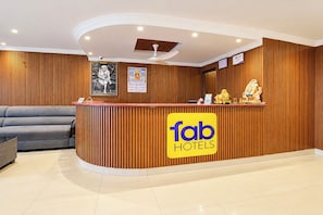 Taulell de recepció d'hotel amb panells de fusta, un sofà i un ventilador de sostre.