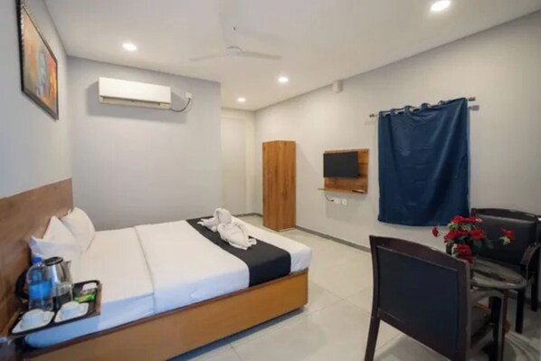 A hotel room with a bed, a desk, a chair, a TV, a wardrobe, and a curtain.
