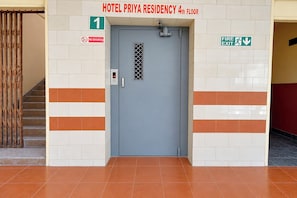 Entrada d'hotel amb una porta grisa, un senyal de 'No Fumar' i un senyal de 'Sortida d'Inc'.