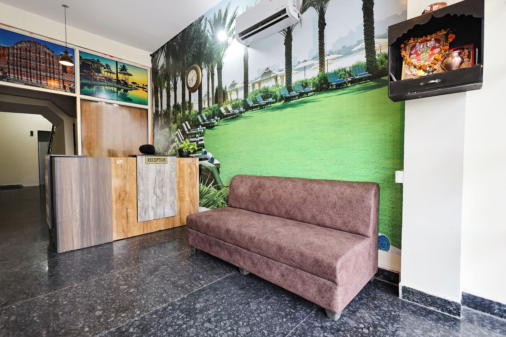 Un área de recepción con mostrador, un sofá, un mural en la pared y un reloj.