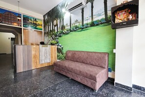 A reception area with a reception desk, a sofa, a wall mural, and a clock.