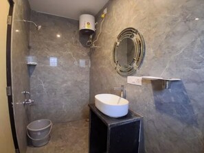 Un bany amb una paret de marbre, un lavabo blanc, una dutxa i un vàter.