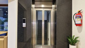 An elevator with a fire extinguisher mounted on the wall beside it.