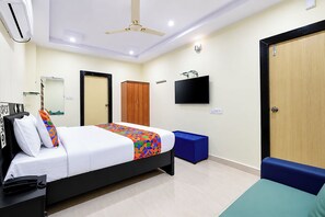 A hotel room with a bed, a television, a wardrobe, and a desk with a telephone.