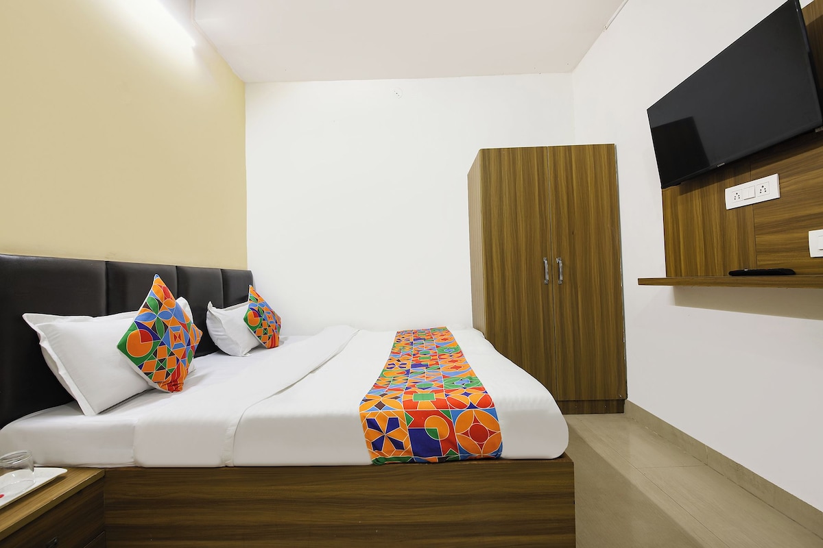 Una habitación de hotel con una cama, un armario, un televisor y una mesita de noche.