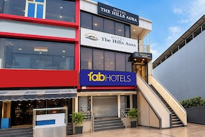 Un hotel de varios pisos con un llamativo letrero 'fabHOTELS', una escalera y un cartel que dice 'Welcome Hotel'.