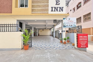 La entrada al Shree Aruna Executive Inn, con un letrero, acceso por portón y plantas en macetas.