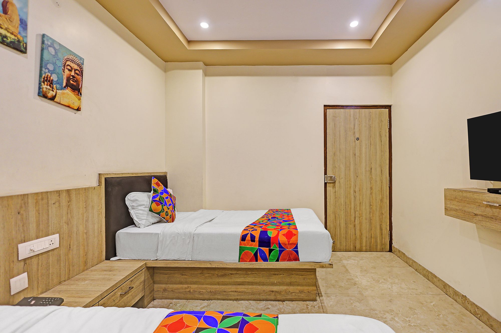 A hotel room with a bed, a television, and a door.