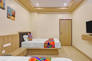 Habitación de hotel con una cama, televisión y puerta.