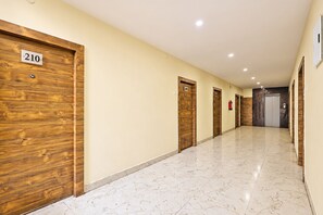 A hotel corridor with wooden doors, numbered 210 and 209, and a fire extinguisher mounted on the wall. - FabHotel Aruna Executive Inn (Visakhapatnam)