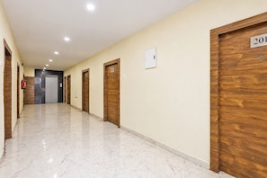 Pasillo de hotel con puertas de madera numeradas 201, 202 y 203, y un extintor de incendios a la izquierda.