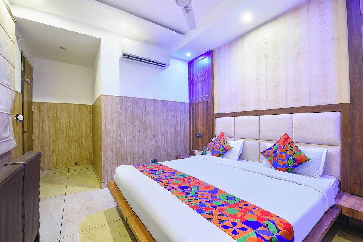 A hotel room with a bed, a wooden wardrobe, an air conditioning unit, and a bathroom.