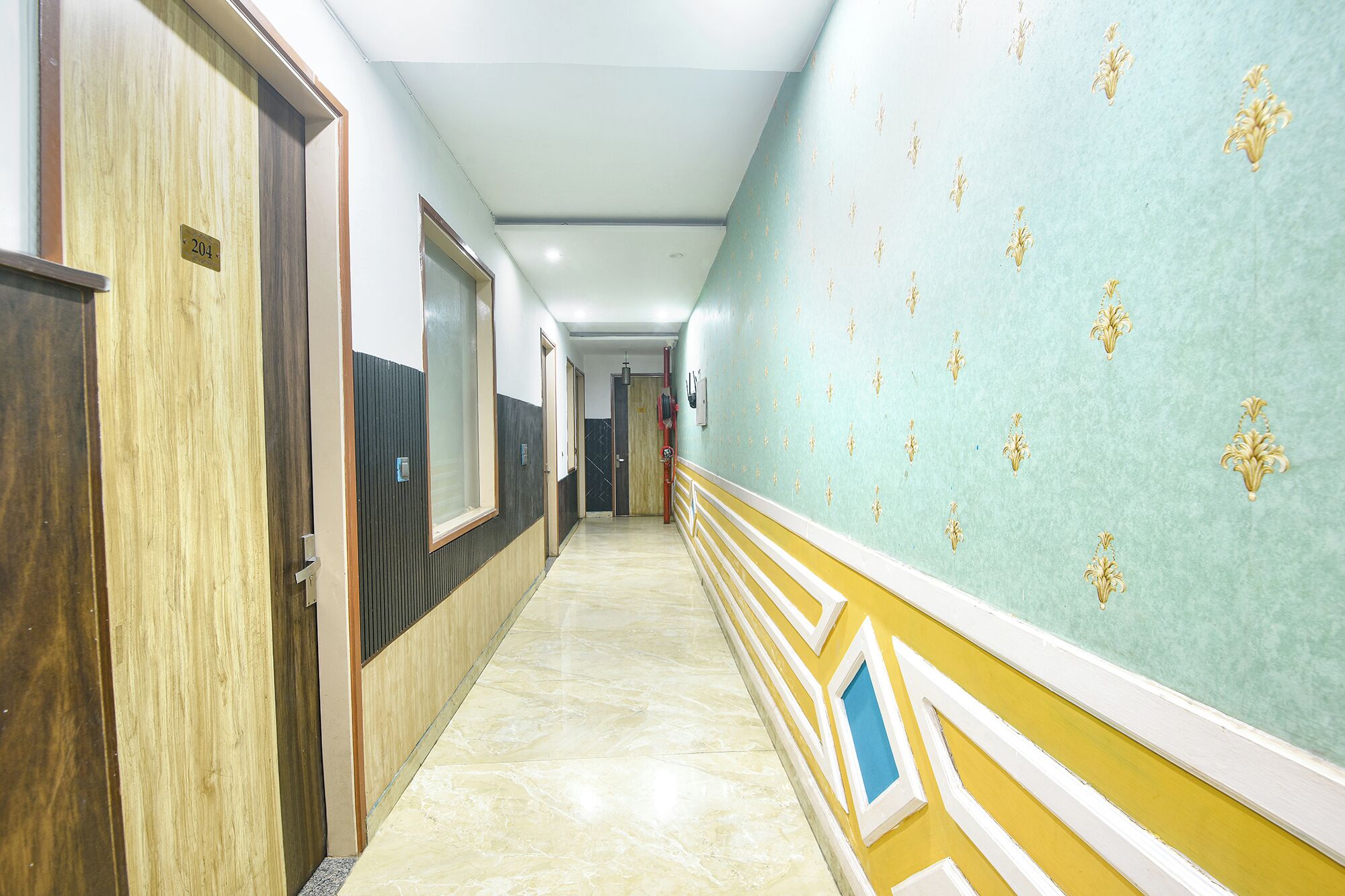 A hallway with doors, a tiled floor, and a wall with a floral pattern.