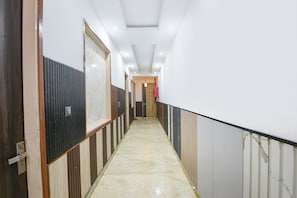 Un pasillo con piso de mármol, paneles de madera en las paredes y puertas que dan a habitaciones.