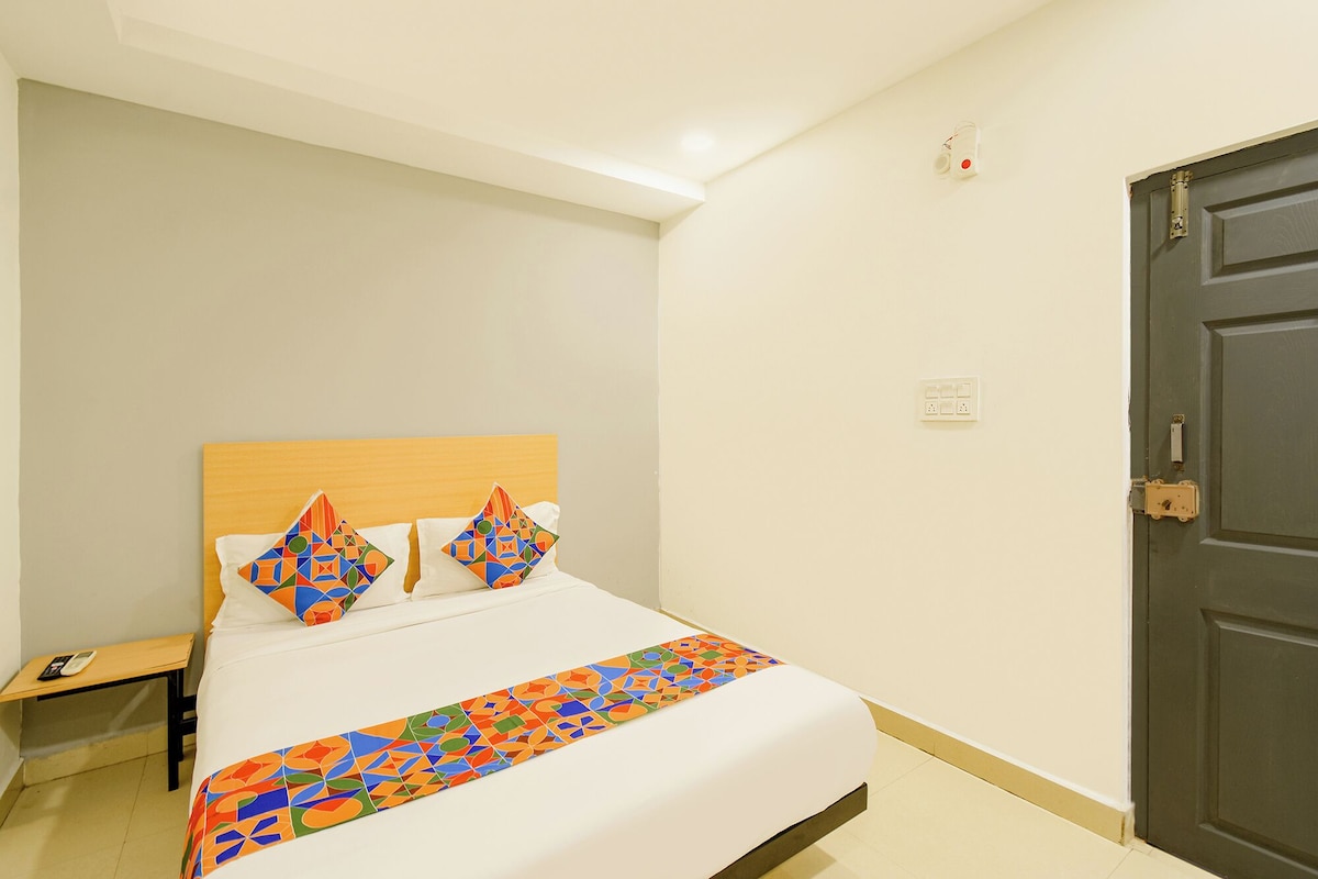 A hotel room with a bed, a bedside table, a nightstand, and a door.