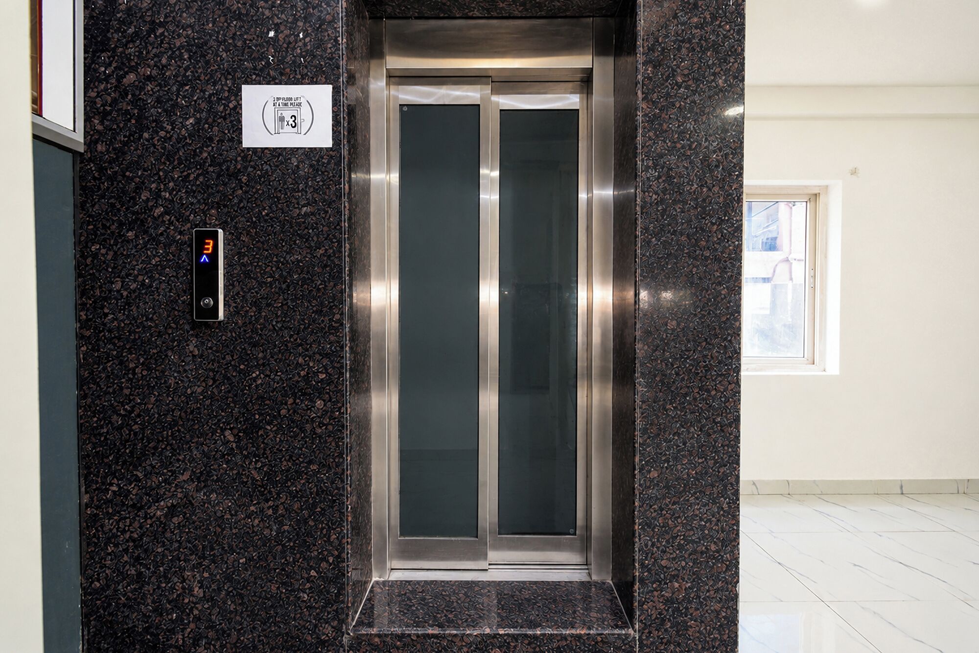 An elevator with a digital display, a sign indicating a lift at a time limit, and a door with a frosted glass panel.