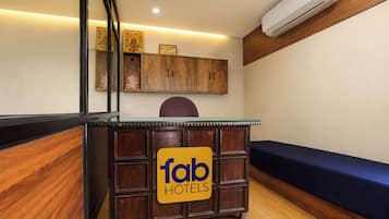 Un comptoir d’accueil avec une enseigne indiquant « fab hotels », des meubles en bois, un canapé bleu et un appareil de climatisation.