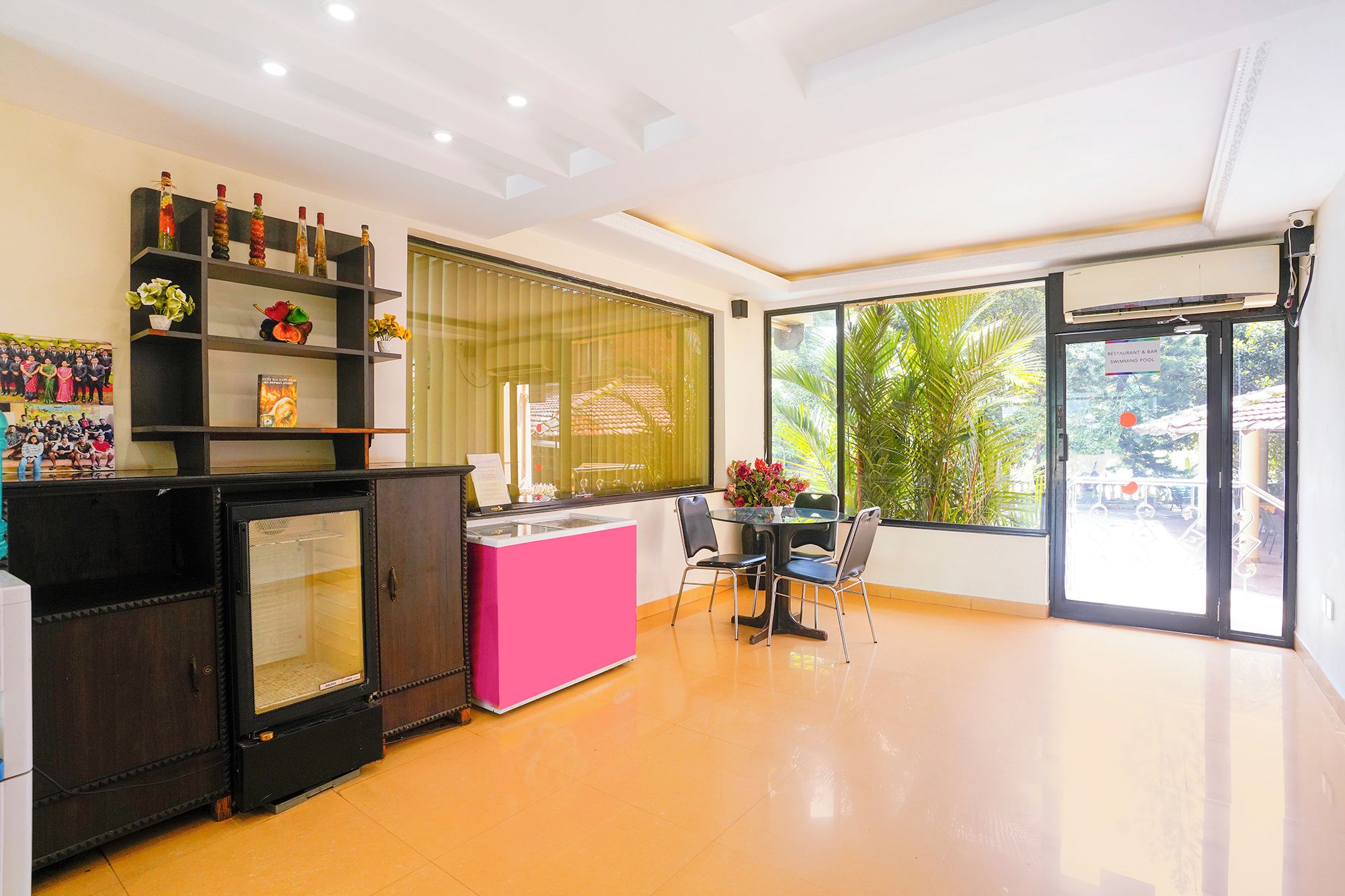 A modern interior with a dining area, a kitchen, and a large window offering a view of the outdoors.