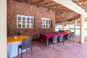 An outdoor dining area with stone walls, wooden ceiling, and tables with chairs. - FabHotel Prime Rendezvous Beach Resort (Panaji)