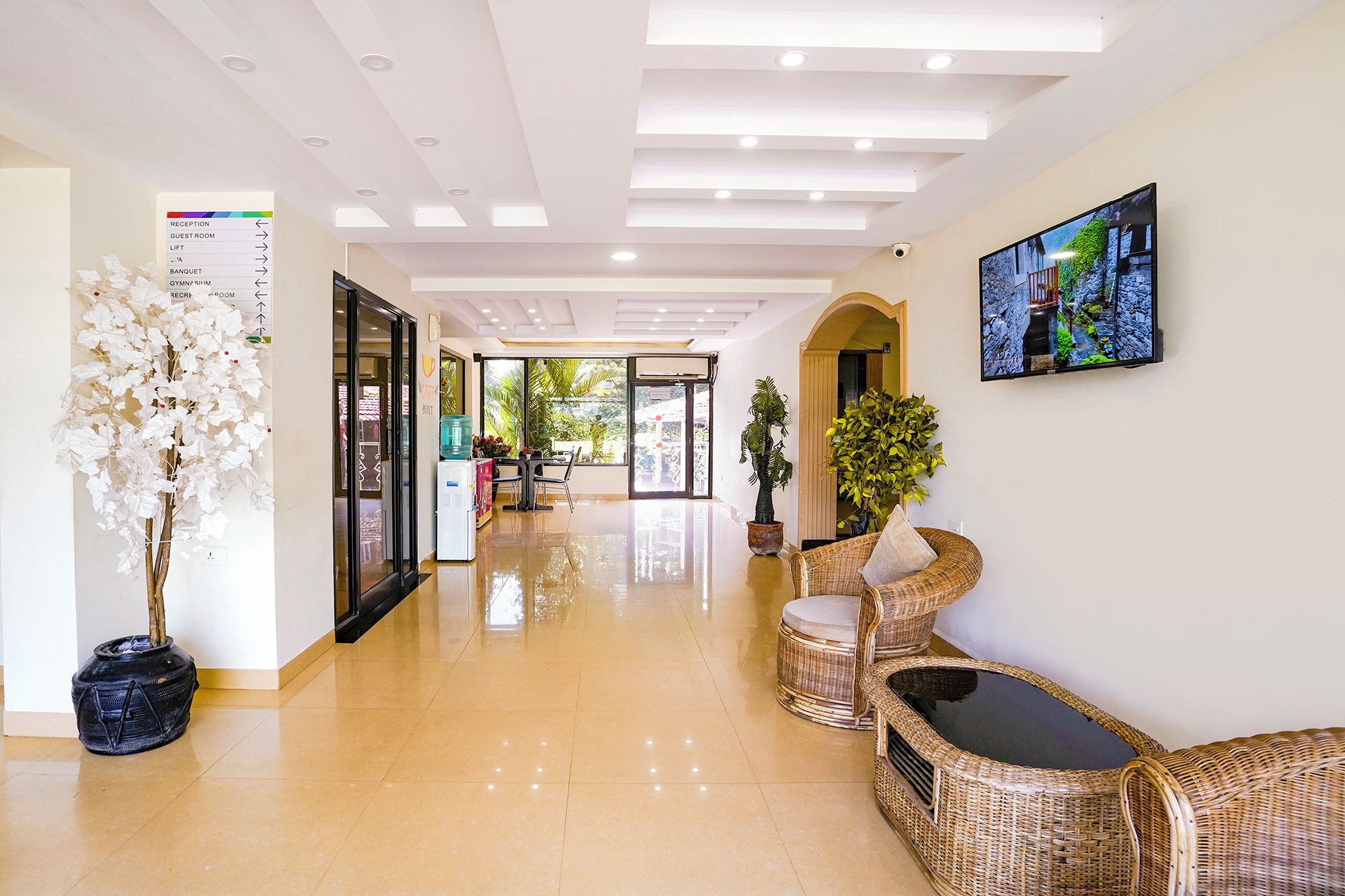 A hotel reception area with a clear floor plan, a reception desk, and a television mounted on the wall.