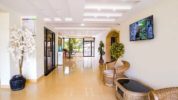 A hotel reception area with a clear floor plan, a reception desk, and a television mounted on the wall.