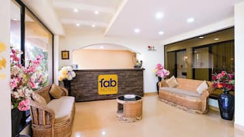 A hotel reception area with a reception desk, wicker furniture, and a sign that reads 'fab hotels'.