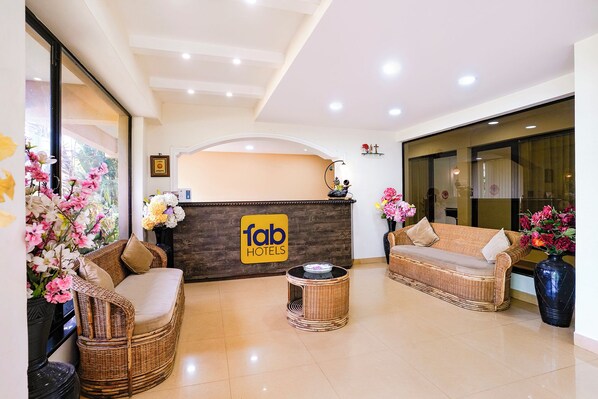 A hotel reception area with a reception desk, wicker furniture, and a sign that reads 'fab hotels'.
