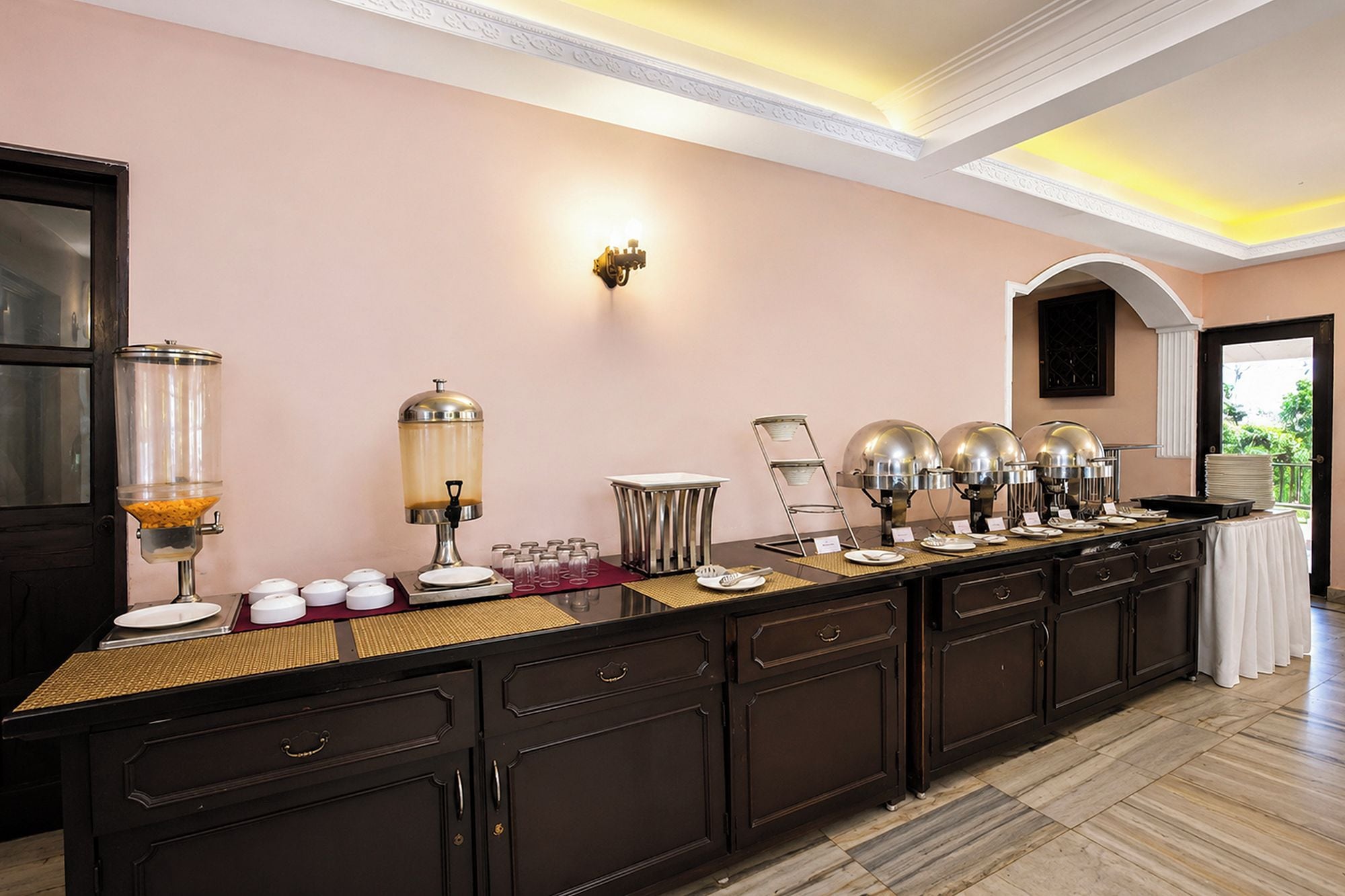 A buffet setup with various food dispensers and a seating area.