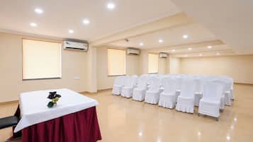 A conference room with a long table, rows of chairs, and ceiling lights.