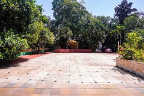 A paved courtyard with a gazebo, surrounded by lush greenery and a parked car. - FabHotel Prime Rendezvous Beach Resort (Panaji)
