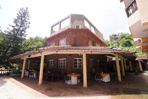 A building with a covered patio area, multiple tables, and chairs.