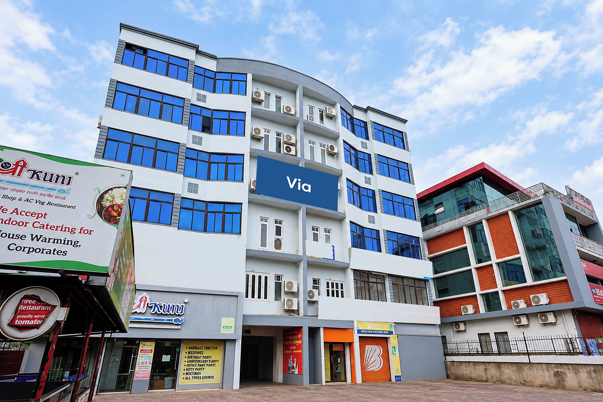 A multi-story building with a blue sign reading 'Via' on the facade.