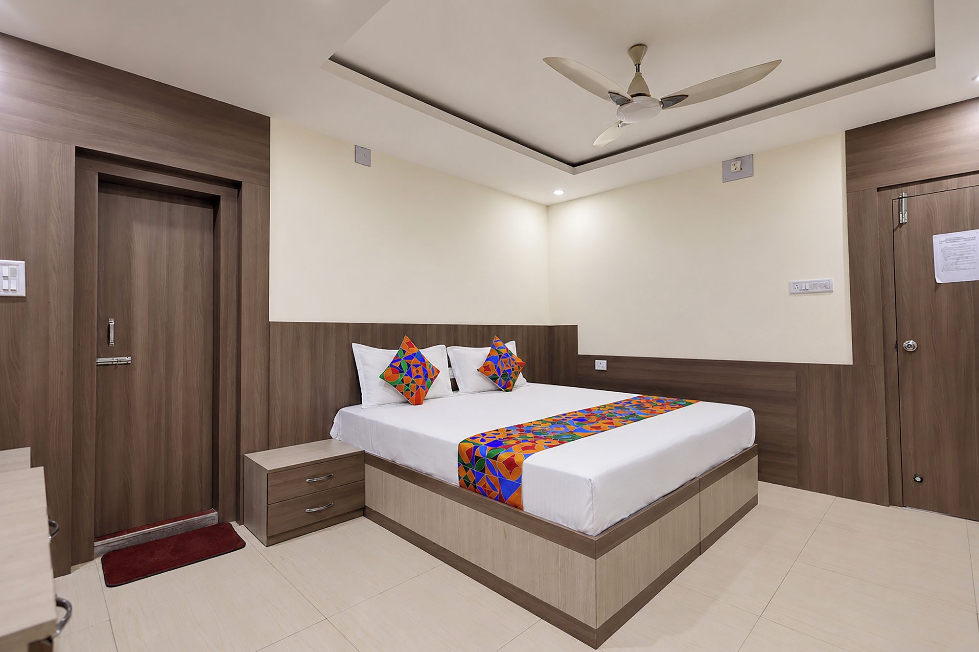 A bedroom with a bed, bedside tables, a ceiling fan, and a red rug.