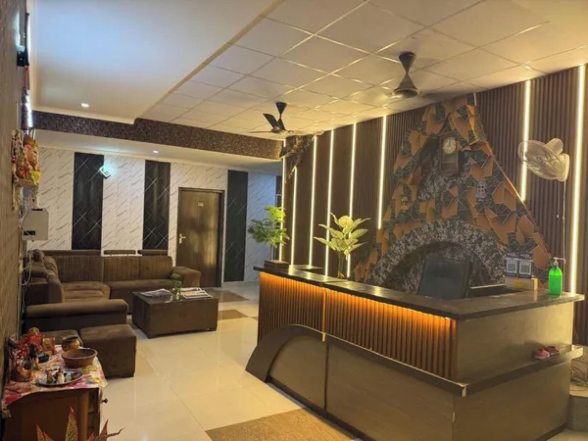 A hotel lobby with a reception desk, seating area, and a decorative wall.