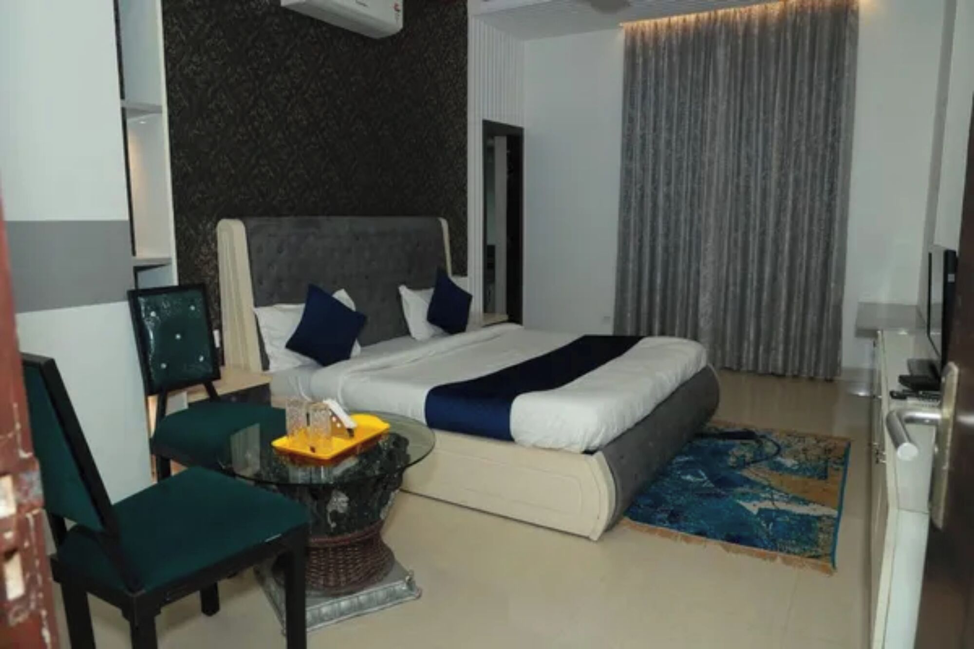 Una habitación de hotel con cama, una silla, una mesita y televisor.