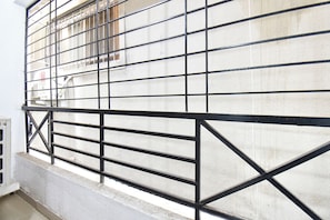 A metal gate with a grid pattern, a concrete wall, and a window with bars.