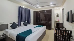 Una habitación de hotel con cama, escritorio, silla, armario y televisor.