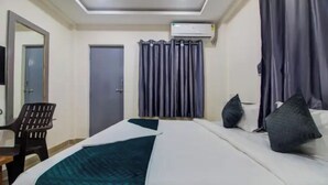 Una habitación de hotel con una cama, una silla, una puerta y un equipo de aire acondicionado.