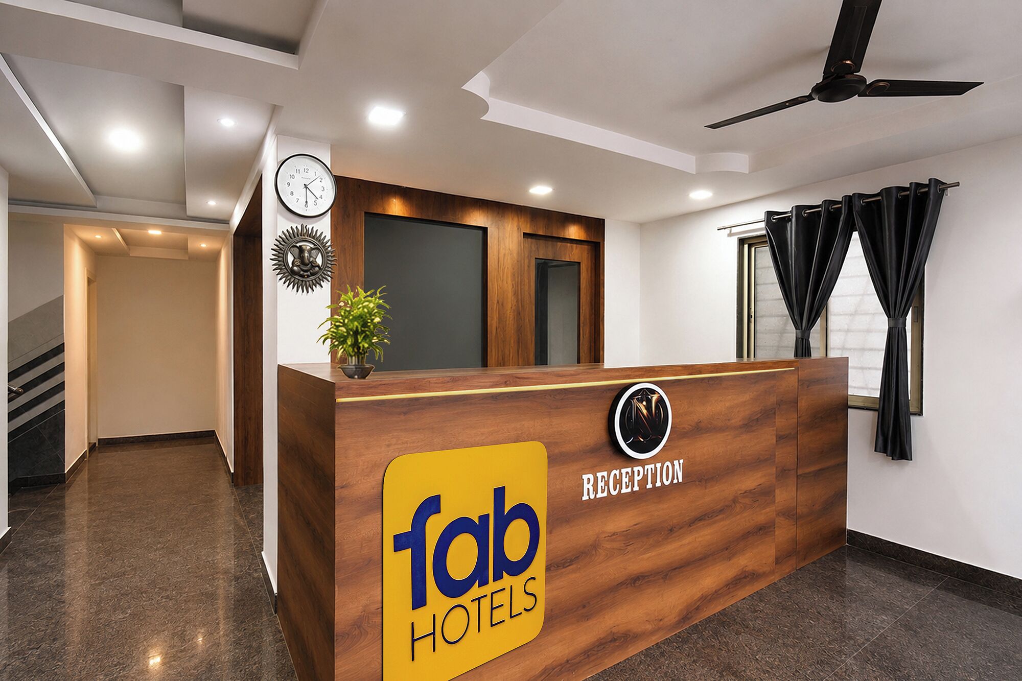 A reception desk with a clock, a potted plant, and a sign for 'fab hotels'.